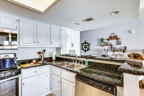 A modern kitchen with white cabinets, a double sink, and a built-in dishwasher.