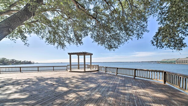 Eine Holzterrasse mit einem Gazebo, umgeben von einem Geländer, mit Blick auf ein Gewässer.