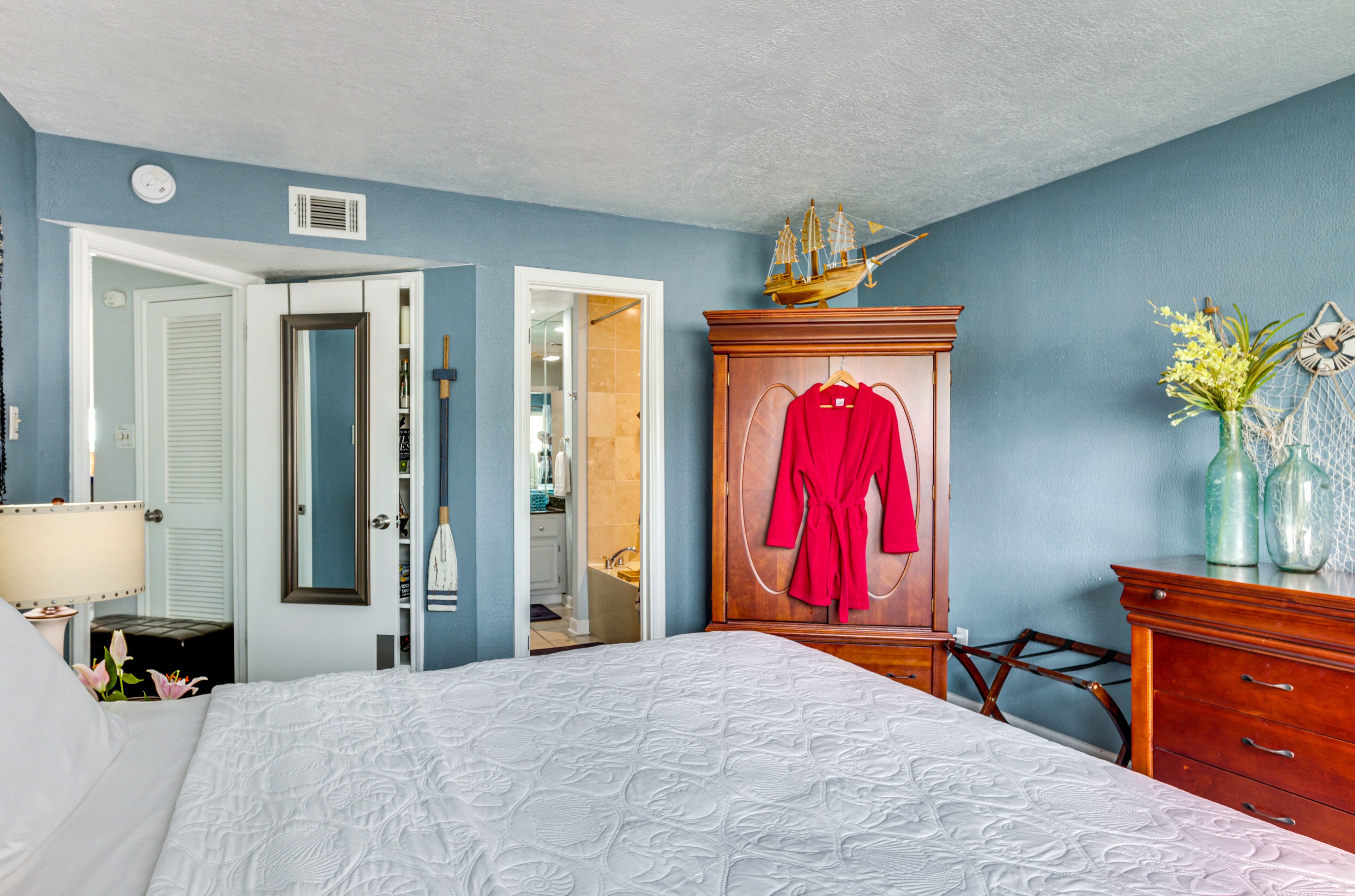 Une chambre à coucher avec un lit, une armoire, un miroir et une commode.