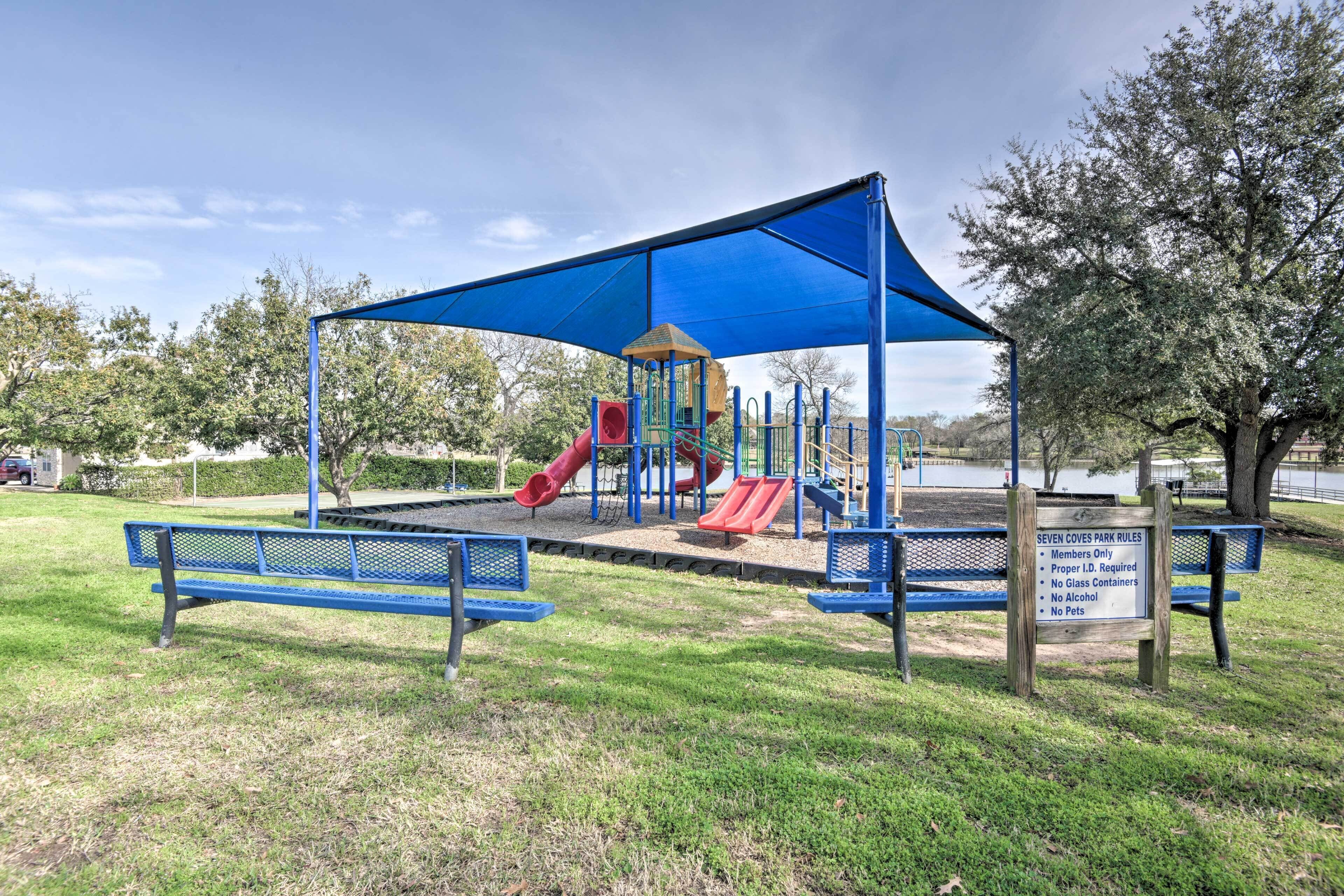 A playground with a blue canopy, slides, and benches.