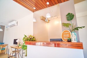 A reception desk with a wooden counter, a computer, and a signboard.
