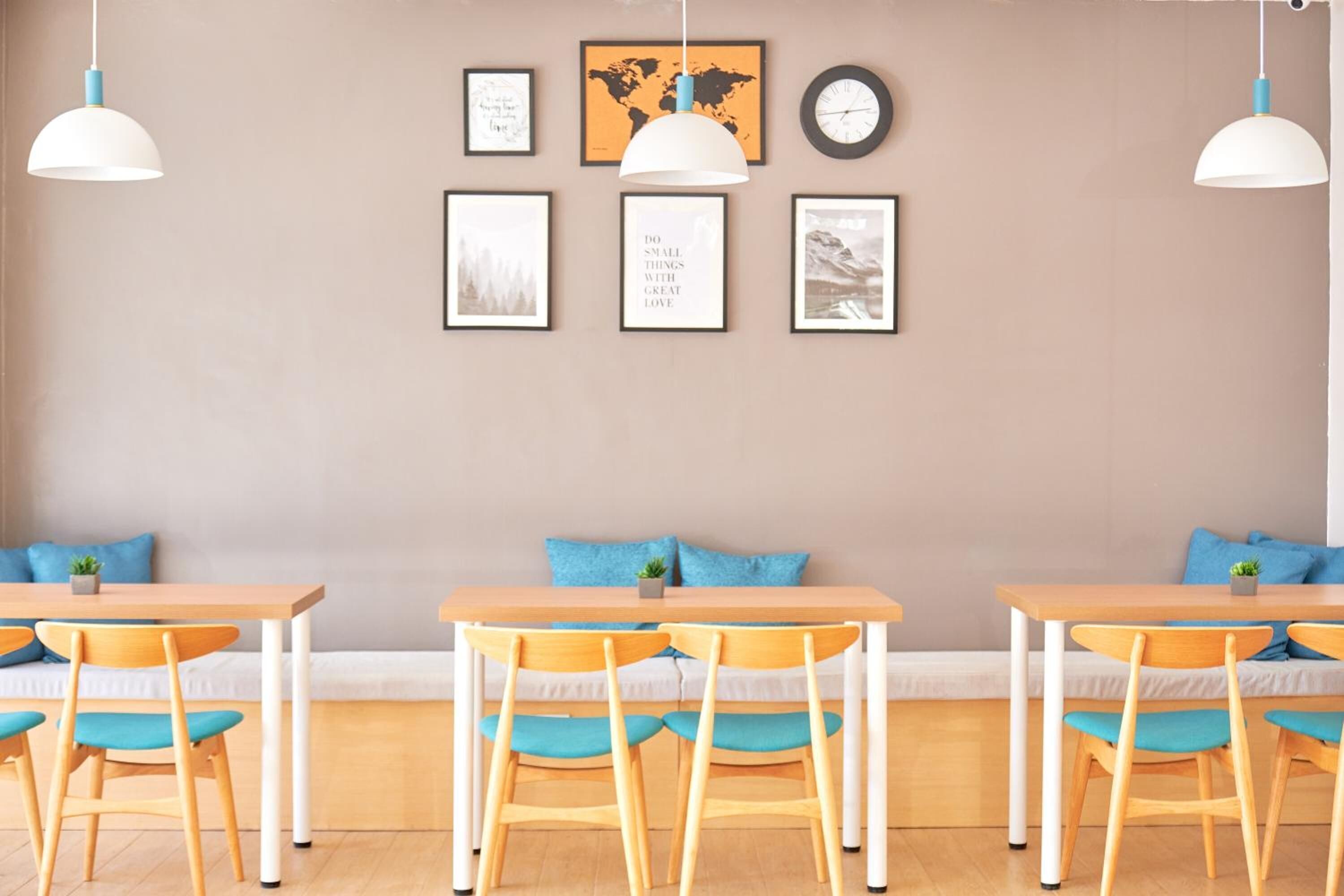 Un comedor acogedor con mesas y sillas de madera, un banco y obras de arte colgadas en la pared.