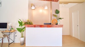 A reception desk with a white counter, a wooden ceiling, and a potted plant. - Bridge Hotel Express (Cagayan de Oro)