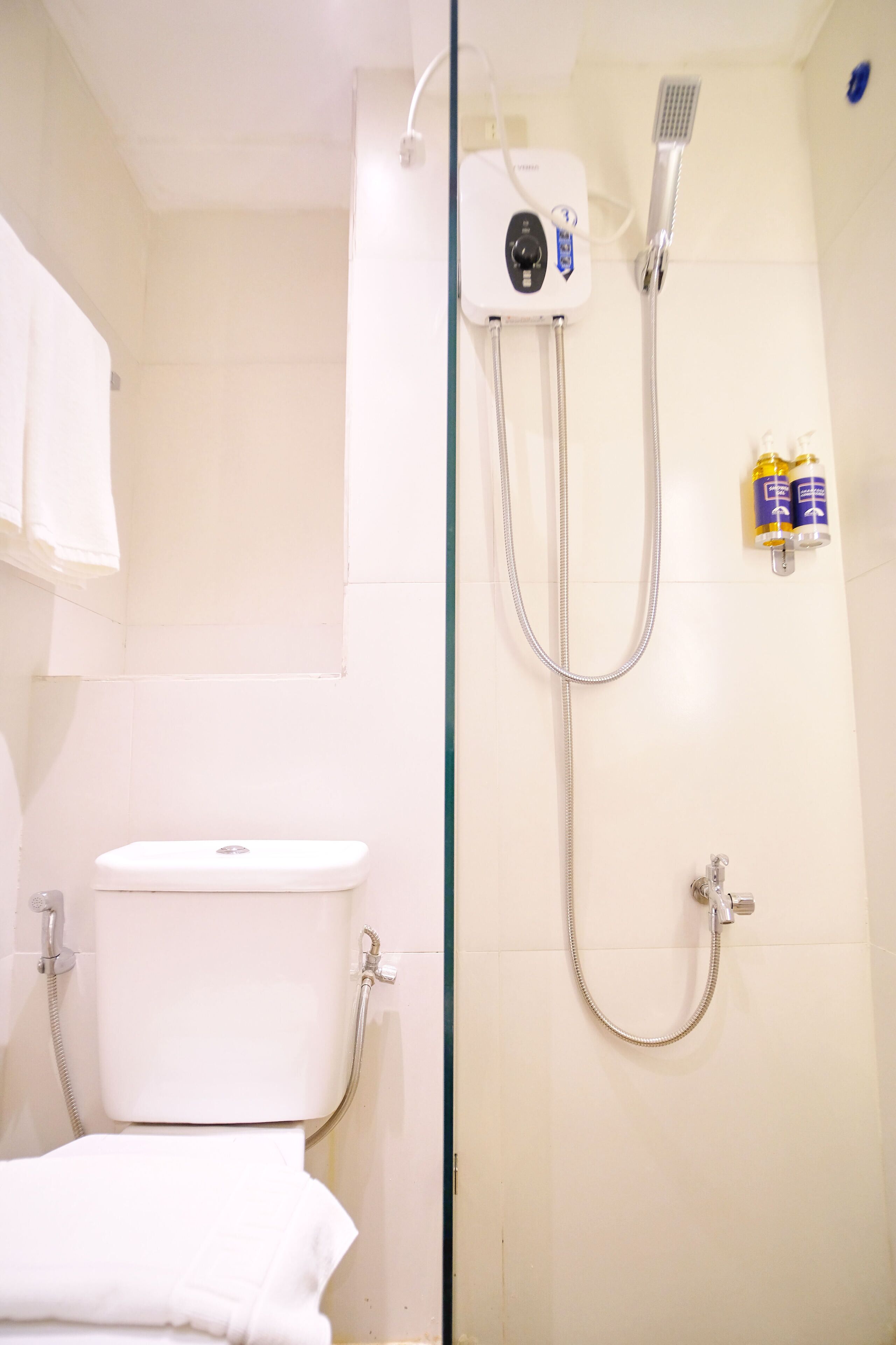 Un baño con ducha, inodoro y perchero para toallas.