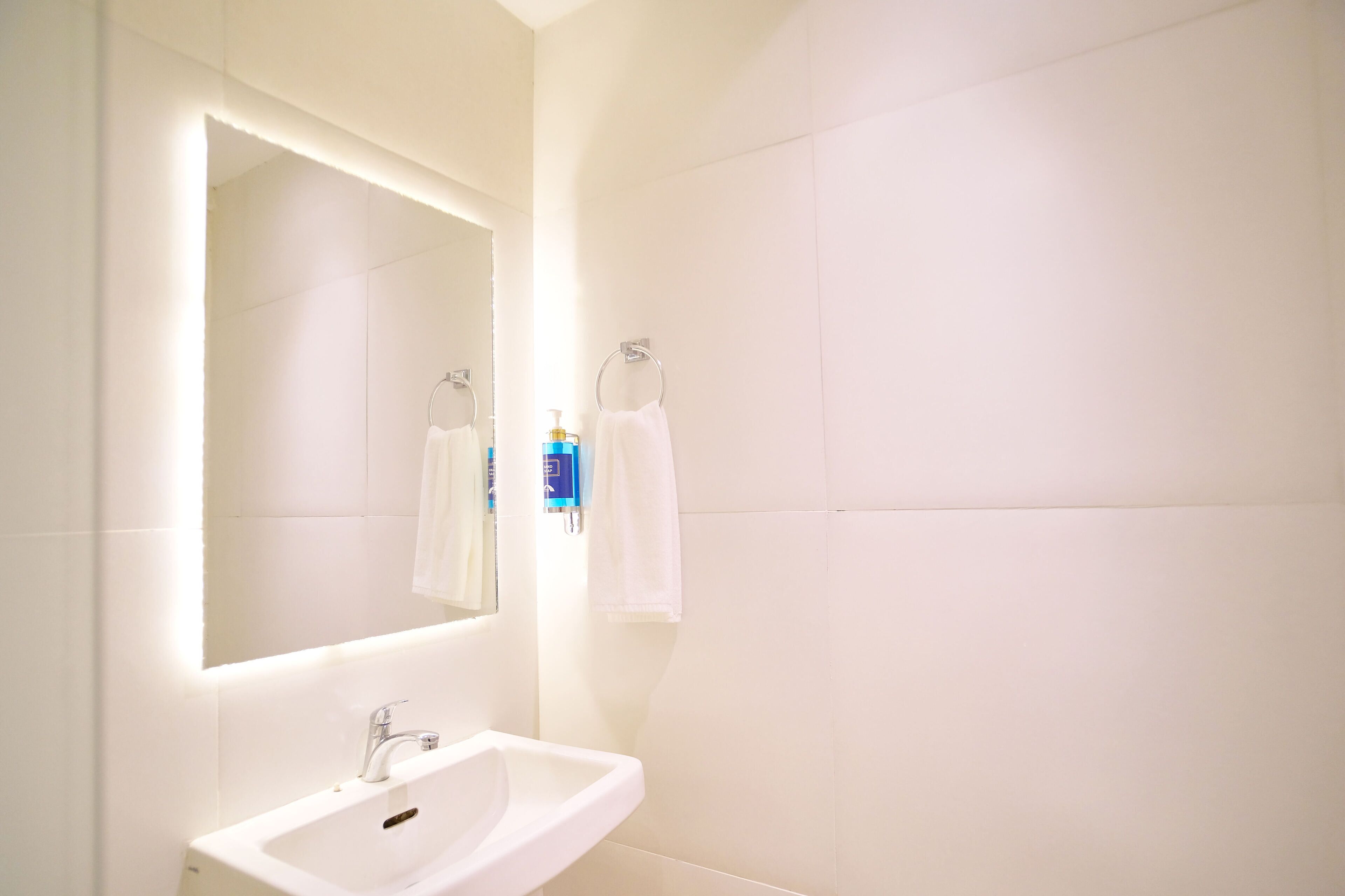 A bathroom with a white sink, a large mirror, and two towels hanging on towel rings.
