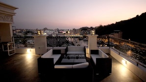 A rooftop terrace with a seating area, a railing, and a view of the cityscape at dusk. - Hama Star (Kaohsiung)