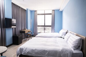 A hotel room with two beds, a desk, a TV, and a window with curtains. - Hama Star (Kaohsiung)