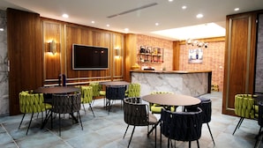 A modern dining area with wooden paneling, a large flat-screen TV, and a brick accent wall. - Hama Star (Kaohsiung)