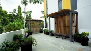 A covered outdoor seating area with potted plants and a bench. - Yello! Hotel (Cebu City)