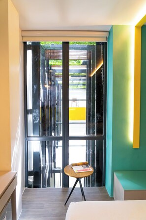 A hotel room with a bed, a small table with a book, and a view through a glass door. - Yello! Hotel (Cebu City)
