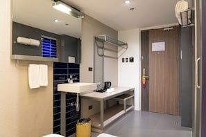 Ein modernes Badezimmer mit Waschbecken, Spiegel, Handtuchhalter und einer Tür mit einem Notausgangsschild.