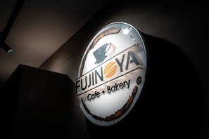 Un letrero circular con el texto 'FUJINOYA Cafe & Bakery' y un logotipo estilizado.