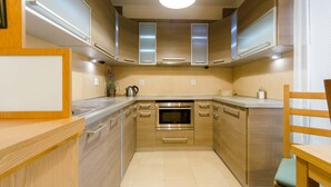 A modern kitchen with wooden cabinets, stainless steel appliances, and a built-in oven. - Good Sleep Family (Kraków)