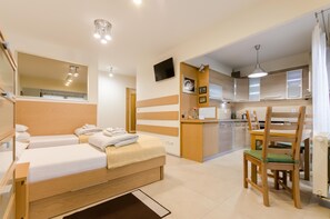 A modern hotel room with two single beds, a kitchenette, a dining area, and a bathroom. - Good Sleep Family (Kraków)