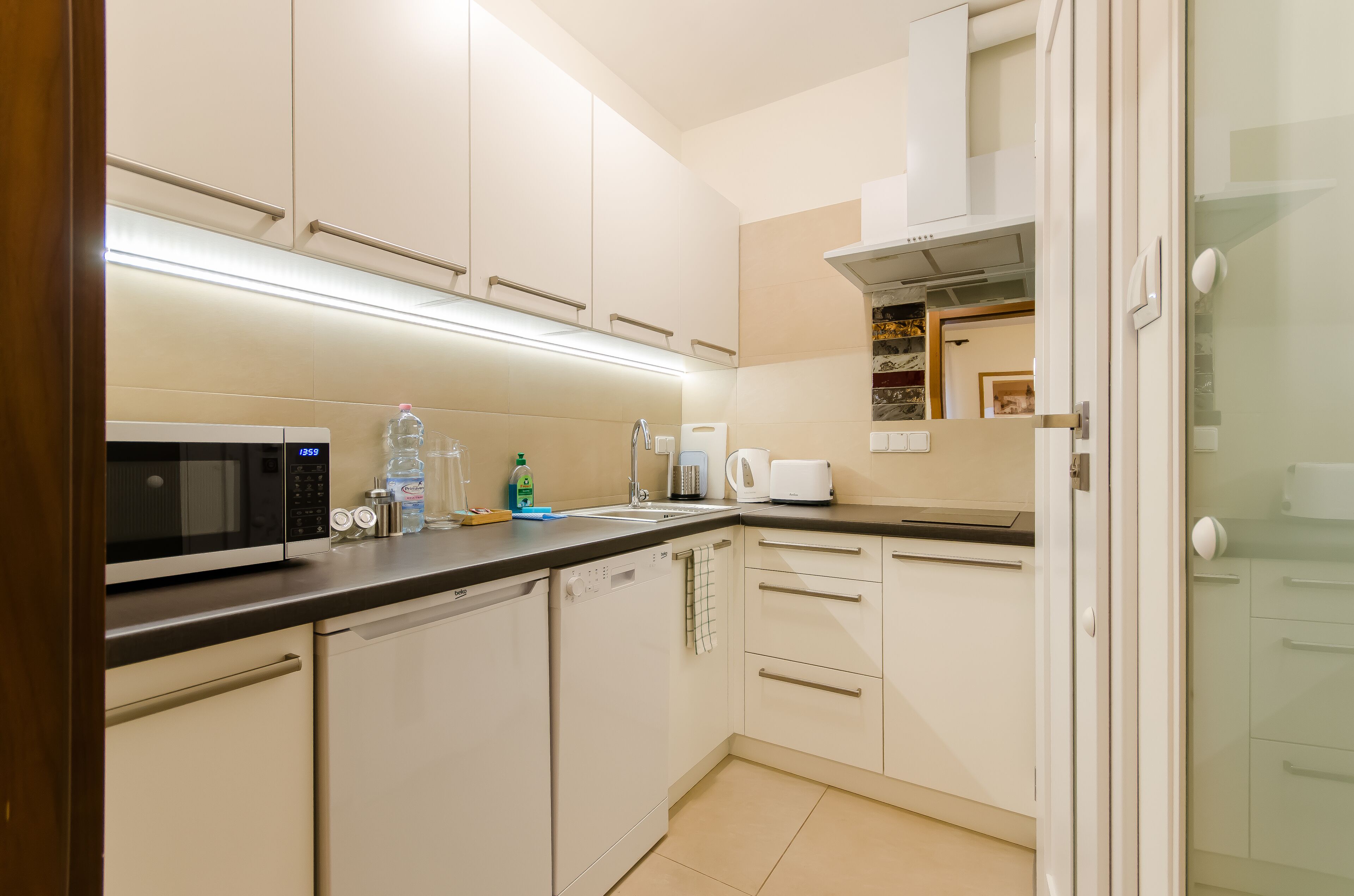 A modern kitchen with white cabinets, a microwave, a coffee maker, and a dishwasher.