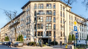 A multi-story hotel with a central entrance, parking signs, and a pedestrian crossing. - Good Sleep Family (Kraków)