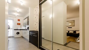 A modern kitchen with a washing machine, a black cabinet, and a glass door leading to a bathroom. - Good Sleep Family (Kraków)