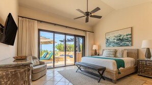 A spacious bedroom with a large bed, a ceiling fan, a view through glass doors to an outdoor area with a pool and lounge chairs.