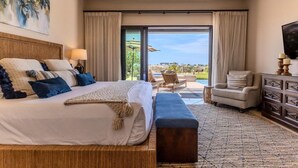 A hotel room with a large bed, a sofa, a TV, and a view of the outdoors.