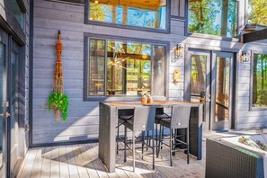 A modern house with a deck, outdoor seating, and large windows.