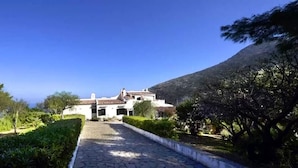 A pathway leading to a building with a tiled roof, surrounded by greenery and trees. - Baglio La Luna (San Vito Lo Capo)