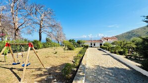 A paved pathway leading to a building with a tiled roof, surrounded by trees and greenery. - Baglio La Luna (San Vito Lo Capo)