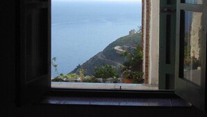 A window with a view of the sea and a hilly landscape. - Baglio La Luna (San Vito Lo Capo)
