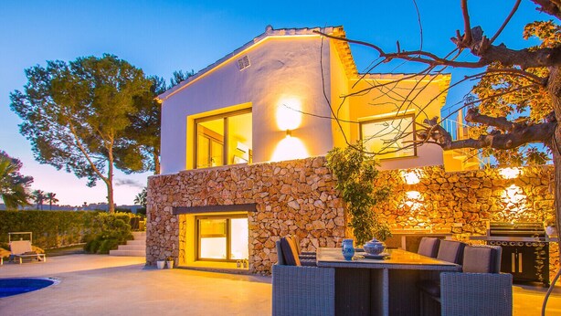 Een modern huis met een stenen gevel, grote ramen en een terras.