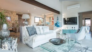 Een moderne woonkamer met een witte bank, een glazen salontafel en een blauwe accentmuur.