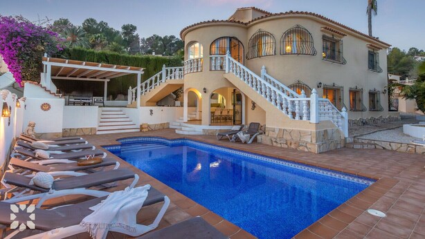 Een groot huis met een zwembad, een overdekte patio en een trap naar een balkon.