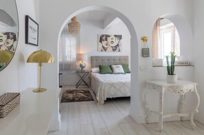 Une chambre à coucher avec un lit, une table de chevet, un miroir et une fenêtre avec des stores.