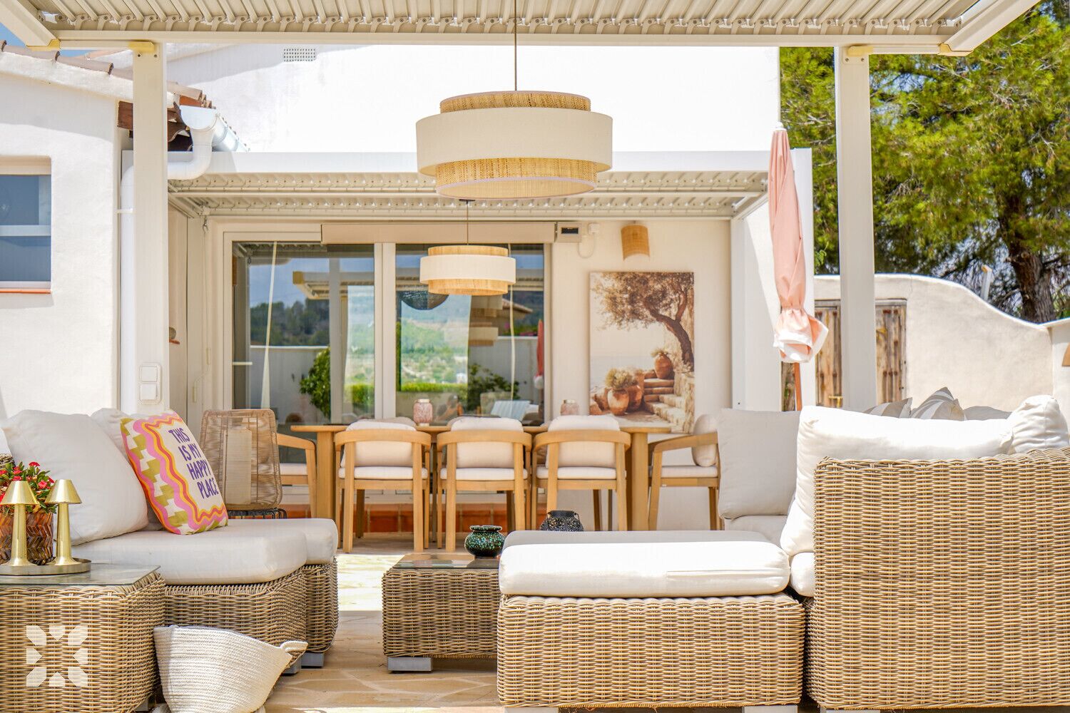 A covered outdoor seating area with wicker furniture, a table, and chairs.