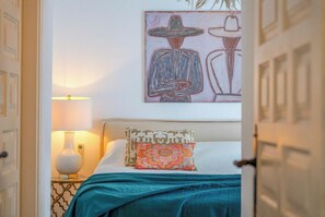 Een hotelkamer met een bed, een nachtkastje met een lamp en een schilderij aan de muur.