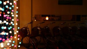 A row of bicycles parked indoors, with colorful lights in the background. - Finest Hour Guesthouse (Chishang)