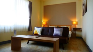 A hotel room with a bed, a sofa, a coffee table, and two bedside lamps. - Finest Hour Guesthouse (Chishang)
