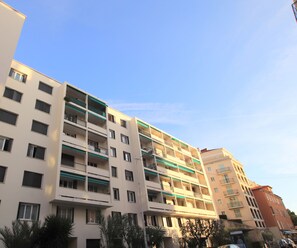 A multi-story residential building with balconies, a flat roof, and a clear sky. - L'anse Lympia (Nice)