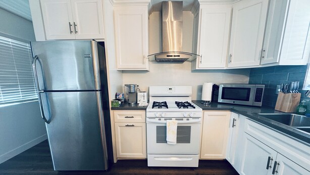 Una cocina moderna con armarios blancos, electrodomésticos de acero inoxidable y suelo de madera.