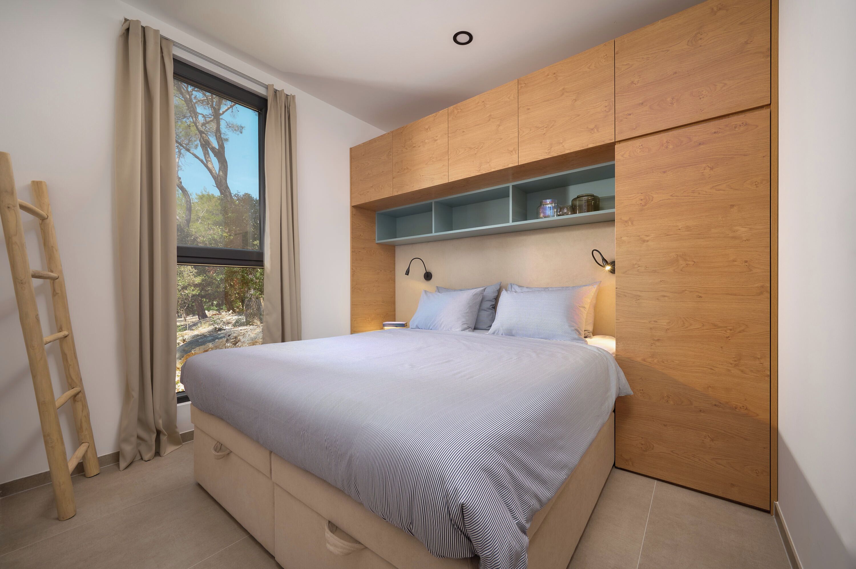 Une chambre à coucher avec un lit, une armoire en bois et une fenêtre avec des rideaux.