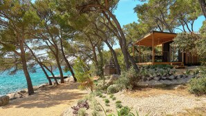 A coastal area with a wooden gazebo overlooking the sea, surrounded by trees and pebbles. - Pine Beach Mobile homes – all inclusive (Pakostane)