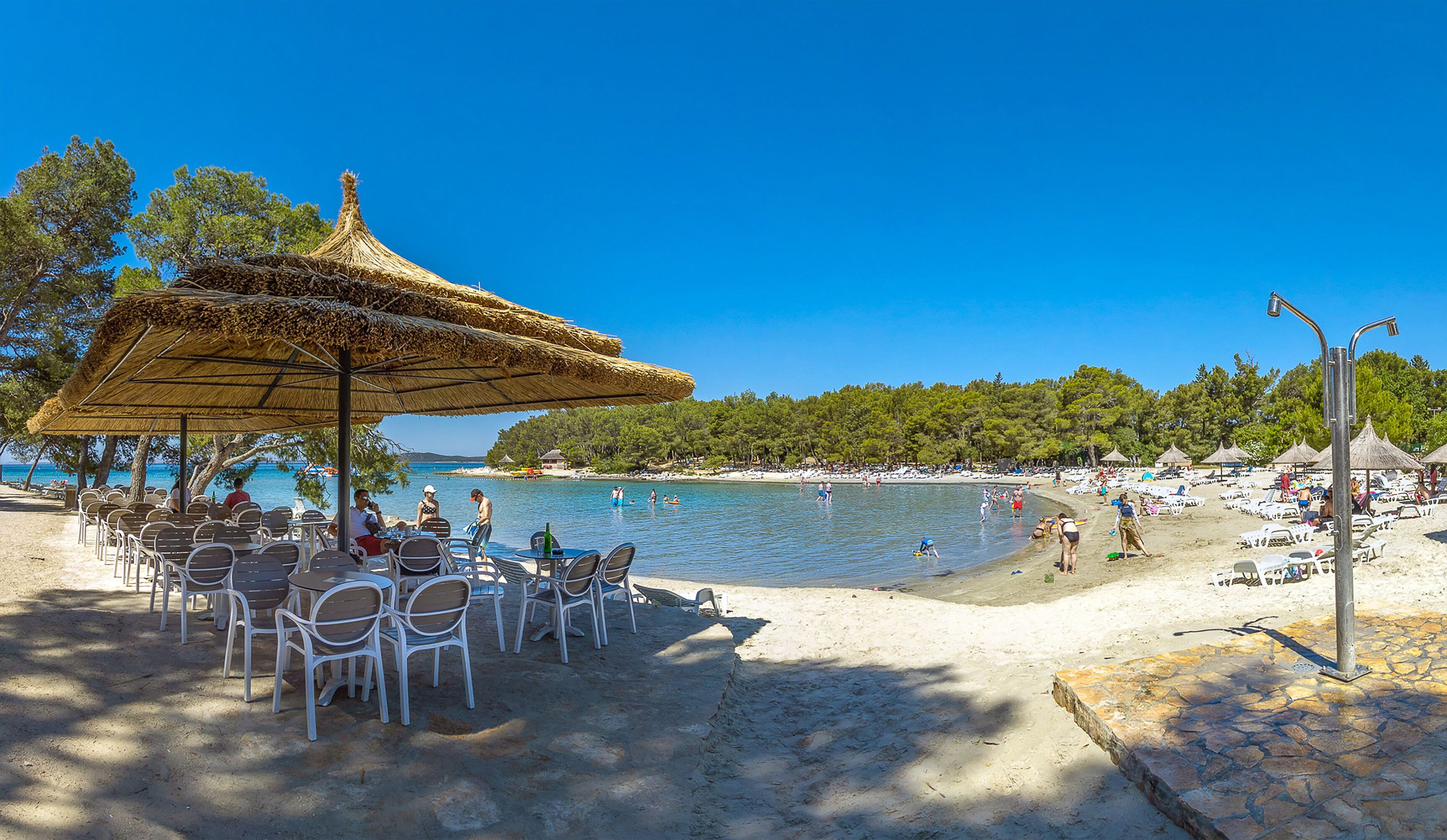 A beachside café with outdoor seating and a view of the sea.