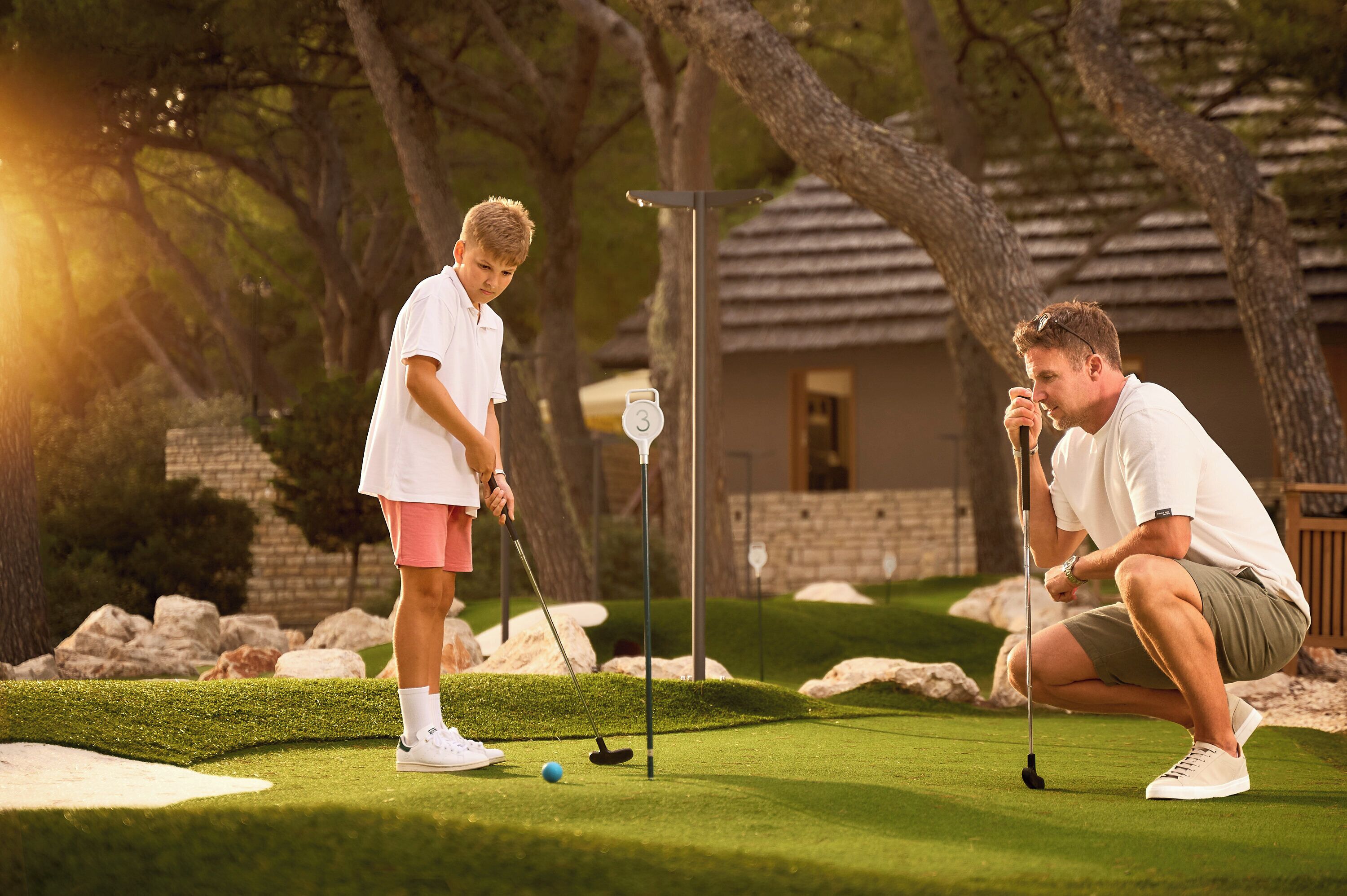 A golf course with a putting green, a golf ball, and a flagstick.