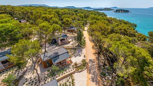 A coastal property with multiple cabins, a sandy path, and a view of the sea and distant islands. - Pine Beach Mobile homes – all inclusive (Pakostane)