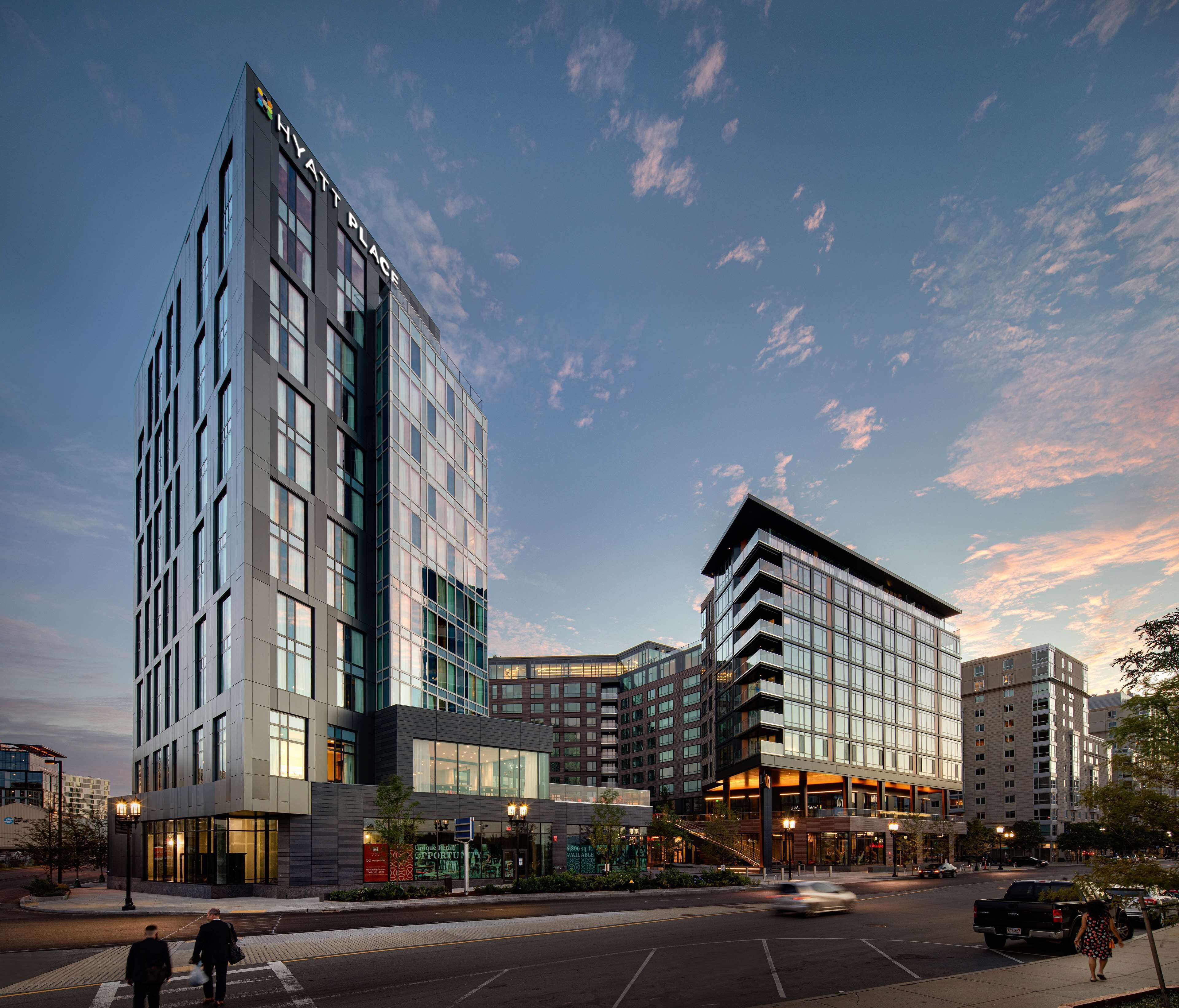 A modern hotel with a prominent glass facade, multiple floors, and a corner entrance.