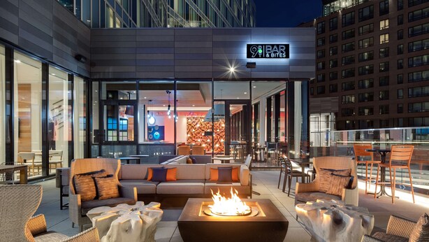 An outdoor seating area with a fire pit, sofas, and chairs. - Hyatt Place Boston/Seaport District (Boston)