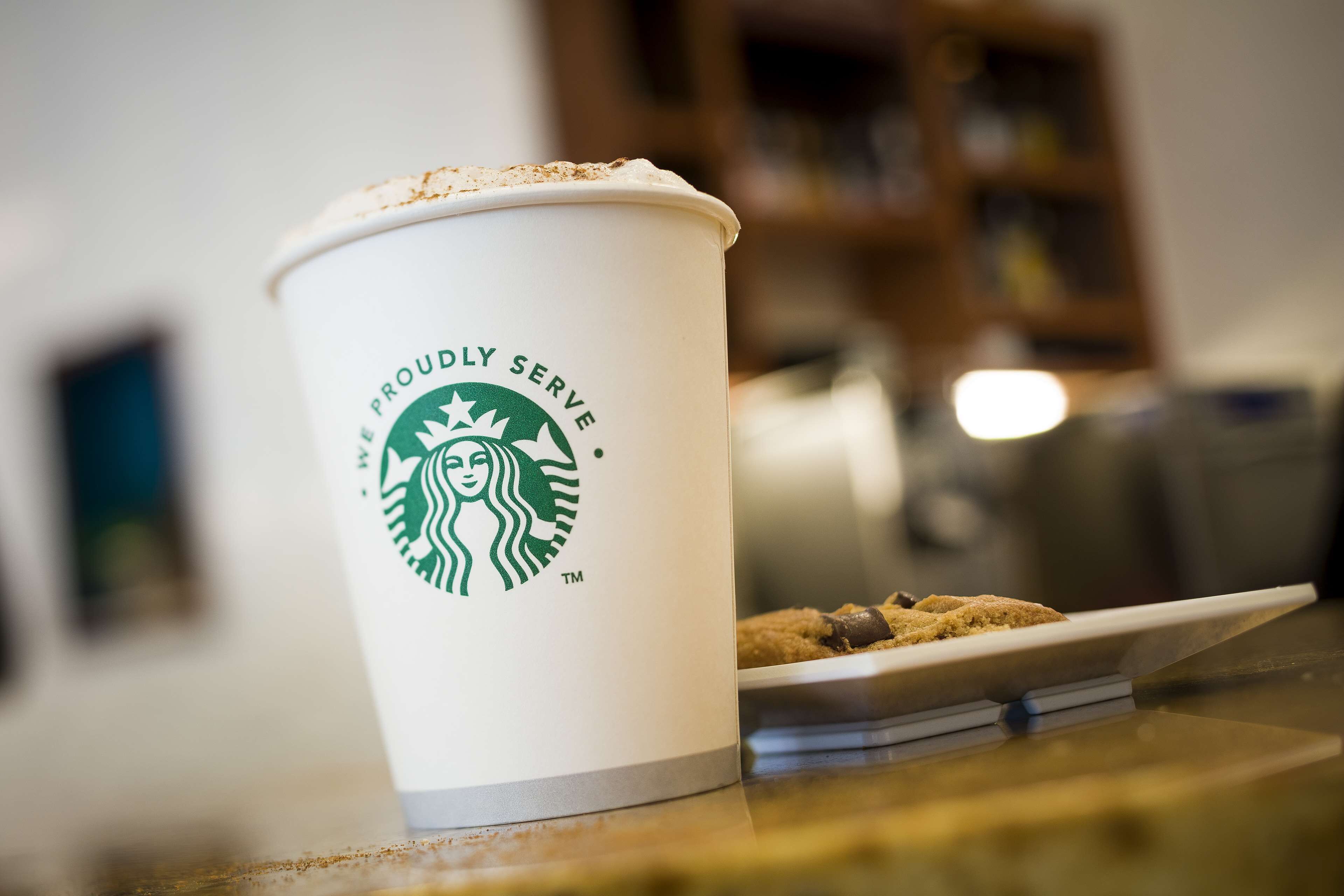 A Starbucks cup with a cookie on a table.