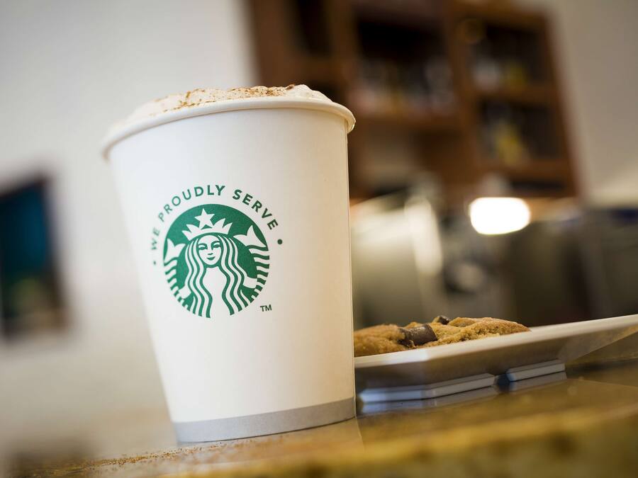 Una taza de Starbucks con una galleta sobre una mesa.