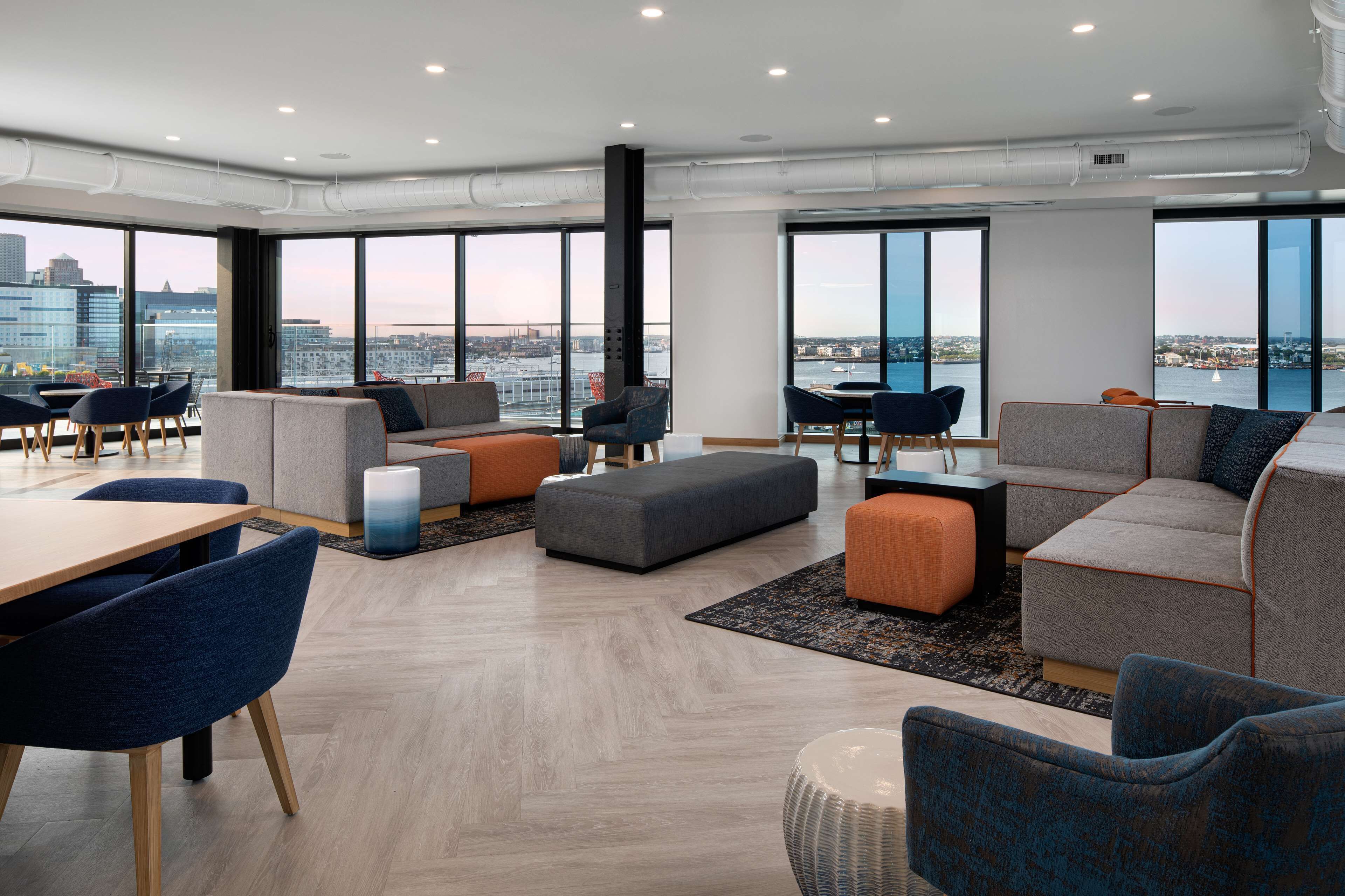 Un ufficio moderno con ampie finestre, soffitto alto e vista sulla città e sull'acqua.