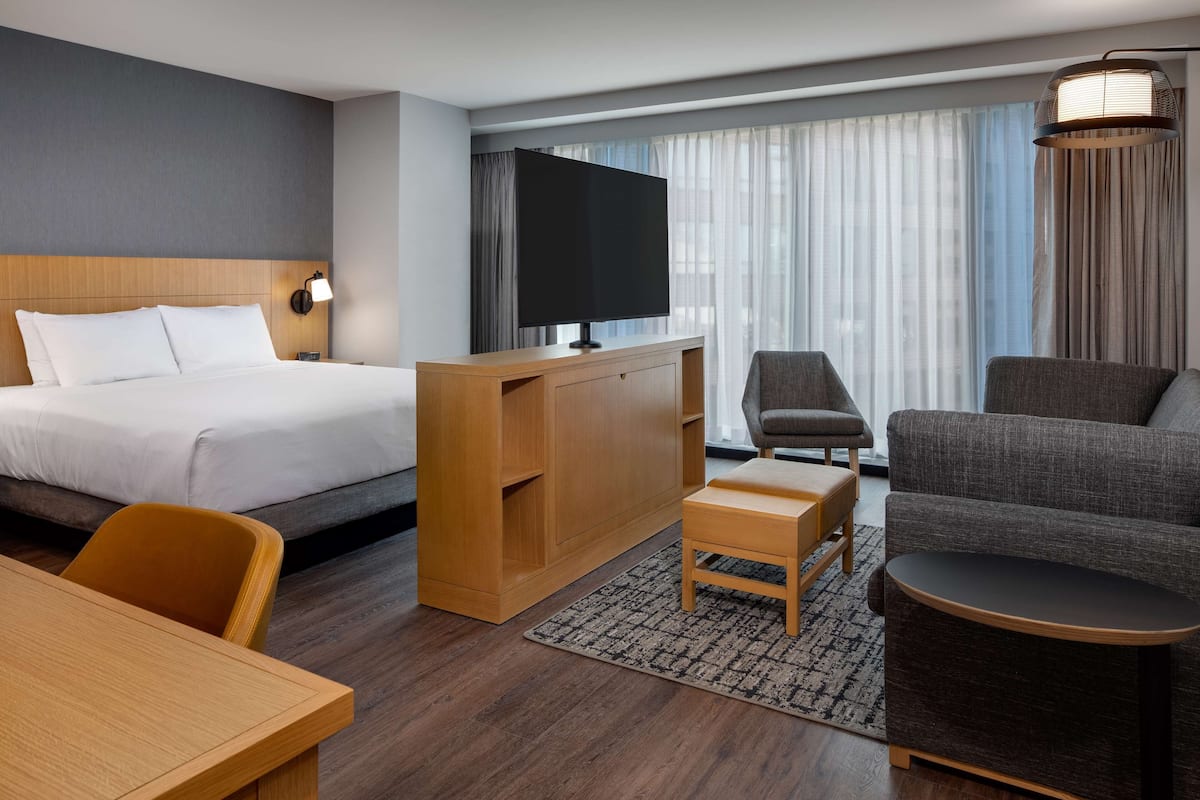 A hotel room with a bed, a desk, a television, a sofa, and a chair.