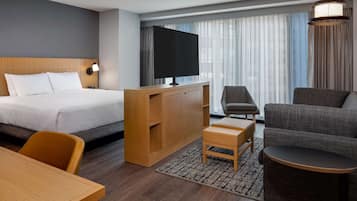 A hotel room with a bed, a desk, a television, a sofa, and a chair.