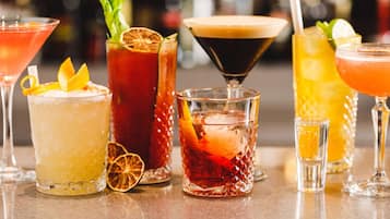 Verschiedene Cocktails in unterschiedlichen Gläsern, darunter ein Martini, ein Highball und eine Margarita, mit Garnituren wie Orangenscheiben und Zitronenzesten.